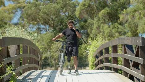 Front-view-of-man-with-bionic-leg-answering-call-during-cycling